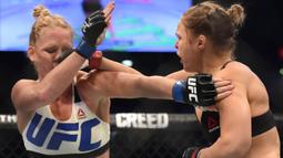 Pukulan dari Ronda Rousey, mendarat di wajah Holly Holm, pada pertarungan perebutan gelar juara kelas bantam UFC Women di Stadion Etihad, Melbourne, Minggu (15/11/2015). (AFP Photo/Paul Crock)