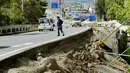 Seorang pria berjalan di dekat jalan yang rusak pasca gempa bumi di kota Mashiki, Prefektur Kumamoto, Jepang selatan, Jumat (15/4). Gempa 6,4 SR yang terjadi Kamis (14/4) itu juga mengakibatkan lebih dari 20 bangunan rumah hancur. (REUTERS/Kyodo)