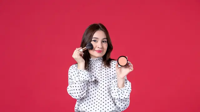 Seorang perempuan sedang mengaplikasikan blush on di pipinya (Foto Dok: Freepik/KamranAydinov)