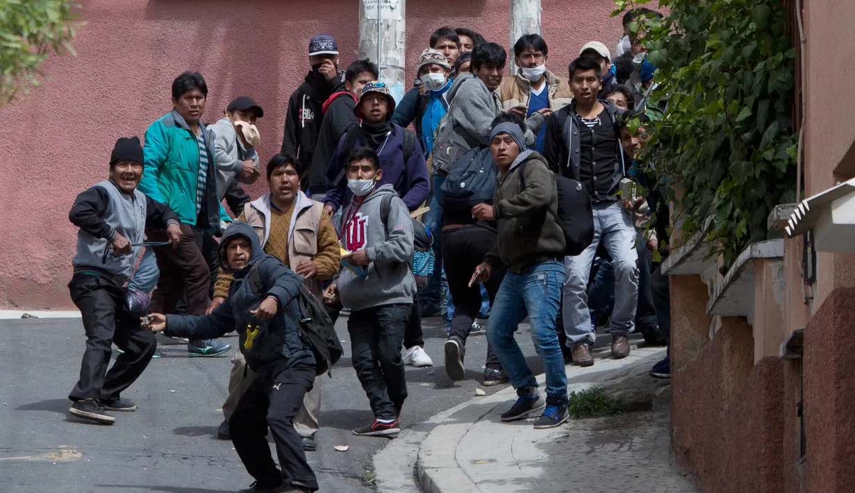 Petani daun koka melemparkan batu saat bentrok dengan polisi di La Paz, Bolivia, Selasa (21/2). Mereka protes kebijakan baru Presiden Evo Morales terkait petani daun koka. (AP Photo / Juan Karita)