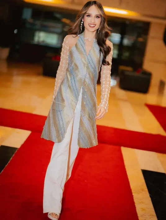 Ia juga mengenakan atasan panjang halter neck model batik dipadukan gloves panjang lace serta celana panjang warna putih. [@claurakiehl]