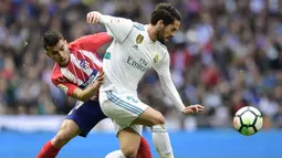 Gelandang Real Madrid, Isco, berebut bola dengan gelandang Atletico Madrid, Angel Correa, pada laga La Liga Spanyol di Stadion Santiago Bernabeu, Madrid, Minggu (8/4/2018). Kedua klub bermain imbang 1-1. (AFP/Javier Soriano)