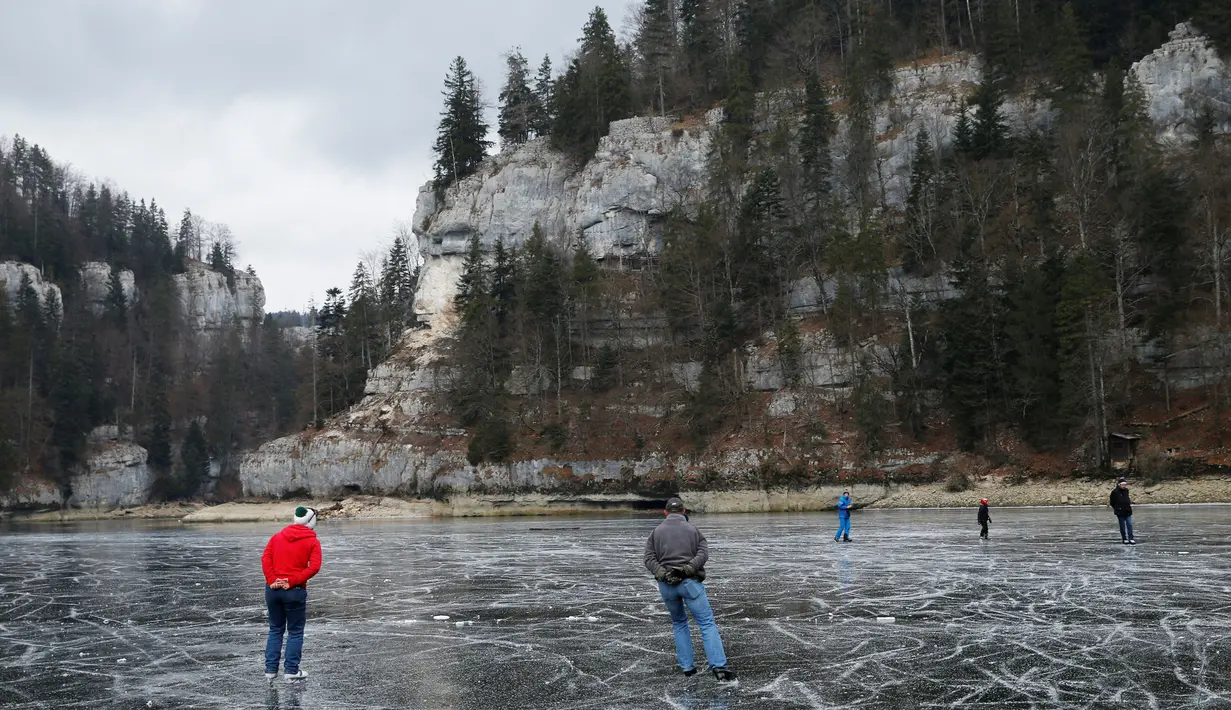 Sejumlah orang asyik bermain ice skating atau seluncur es di atas sungai Doubs yang membeku di perbatasan Perancis Les Brenets, Swiss, Senin (2/1). Sungai ini menjadi objek wisata es yang diminati warga. (REUTERS/Denis Balibouse)