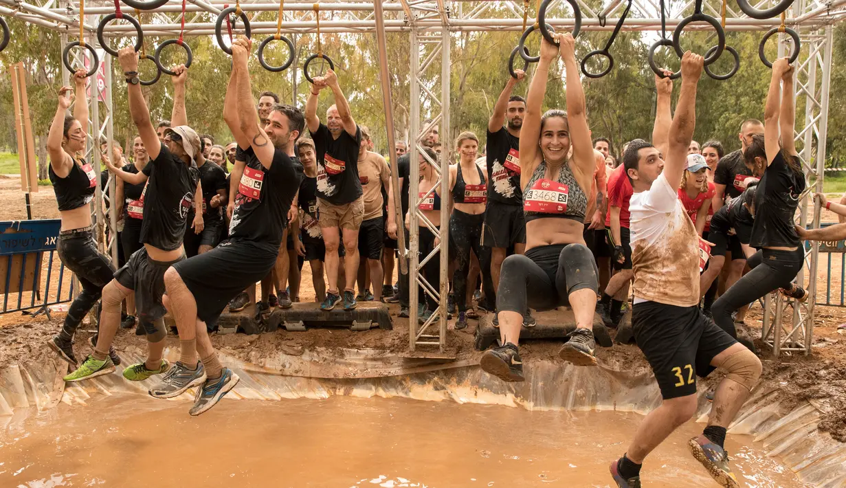 Sejumlah peserta melewati rintangan saat mengikuti Mud Day di Tel Aviv, Israel (16/3). Para peserta harus menyelesaikan lomba lari sepanjang 13 kilometer yang dipenuhi rintangan dan kubangan. (AFP Photo/Jack Guez)