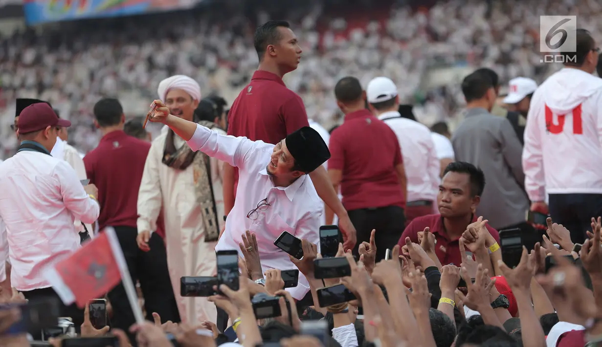 Ustaz Yusuf Mansur berselfie dengan pendukung pasangan Capres dan Cawapres nomor urut 01, Jokowi - Ma'ruf Amin saat mengikuti kampanye akbar bertajuk 'Konser Putih Bersatu di Stadion Gelora Bung Karno (SGBK), Jakarta, Sabtu (13/4). (Kapanlagi.com/Budi Santoso)