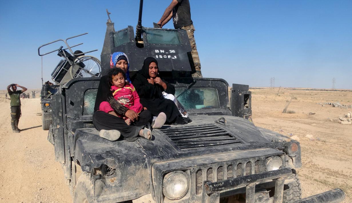 Warga duduk dibagian depan mobil saat melarikan diri setelah terjadinya pertempuran antara pasukan Irak dan militas ISIS di kota Hit, provinsi Anbar, (5/4/2016). (REUTERS/Stringer)