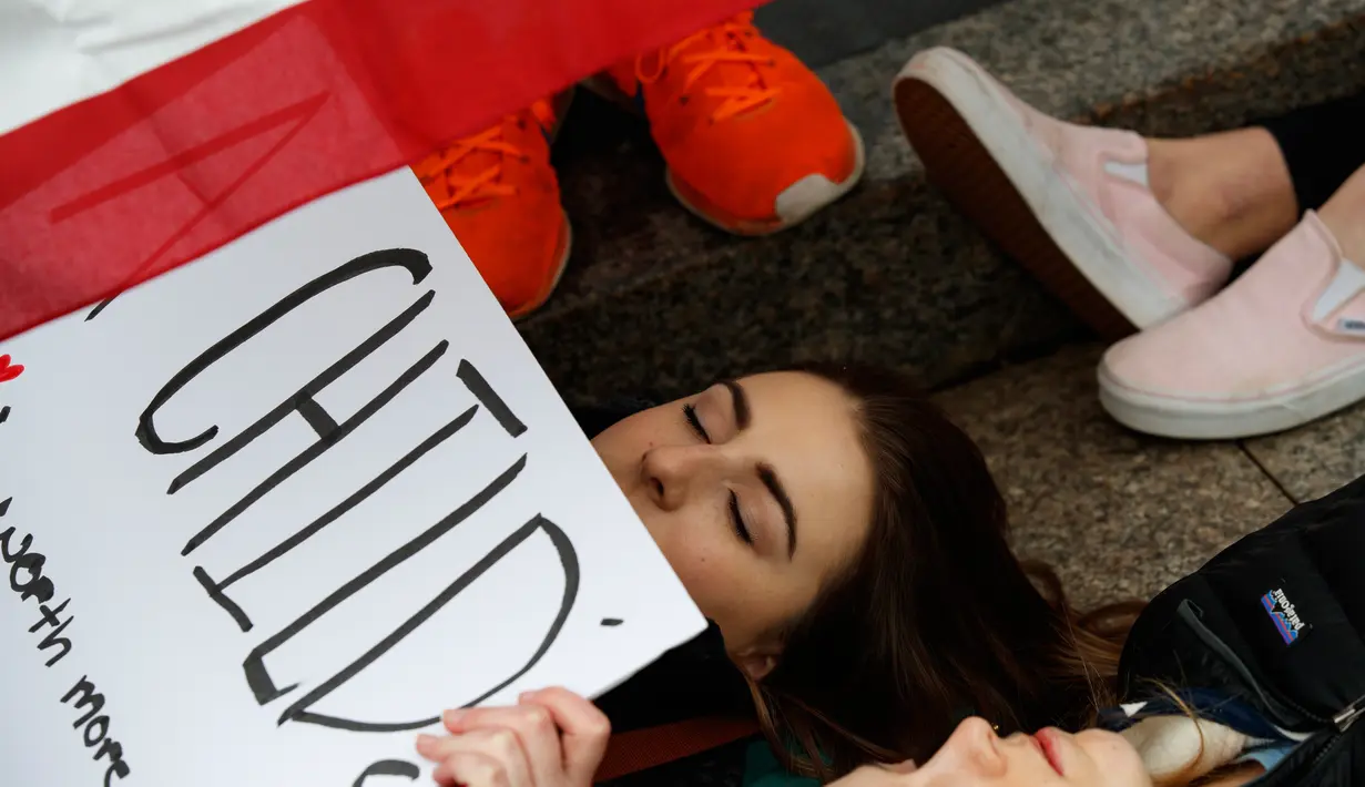Anna Hurley (15) bersama dengan pengunjuk rasa lainnya berbaring di jalan depan Gedung Putih, Washington, Senin (19/2). Aksi mereka merupakan simbol dari para korban tewas penembakan sekolah di Florida pekan lalu. (AP Photo/Evan Vucci)