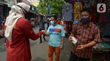 Petugas membagikan masker kepada warga di Pasar Jatinegara, Kamis (10/9/2020). Petugas gabungan terus melakukan himbauan untuk memakai masker dan membagikan masker di pasar tersebut. (merdeka.com/Imam Buhori)