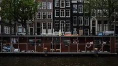 Pejalan kaki melintas dekat Catboat, tempat penampungan berbentuk kapal yang terapung di Amsterdam, Belanda, 3 Agustus 2017. Catboat sangat terkenal sebagai tempat perlindungan untuk para kucing jalanan yang terlantar. (AP Photo/Muhammed Muheisen)