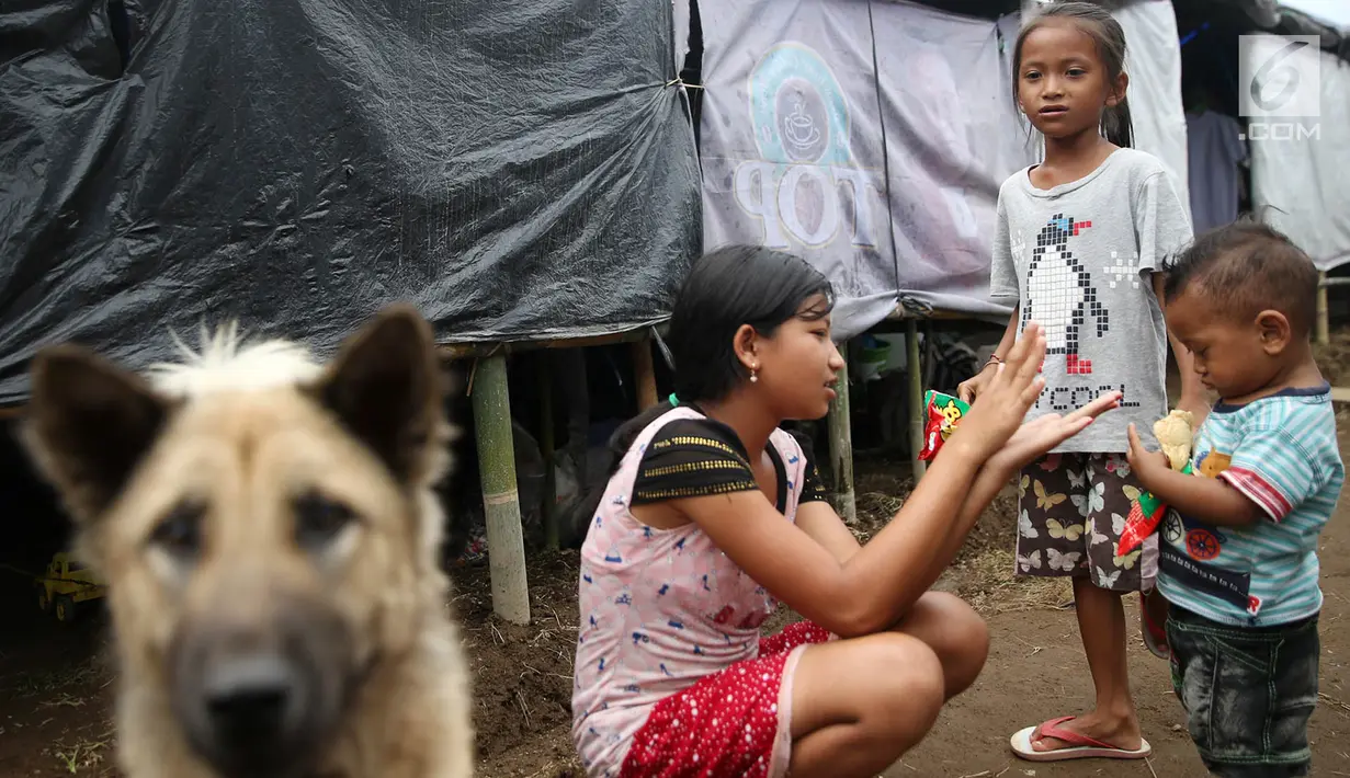 Anak-anak bermain di sekitar tenda Posko Pengungsi Rendang, Bali, Sabtu (2/12). Erupsi Gunung Agung membuat anak-anak tersebut terpaksa harus bermain di posko pengungsian dengan kondisi yang seadanya. (Liputan6.com/Immanuel Antonius)