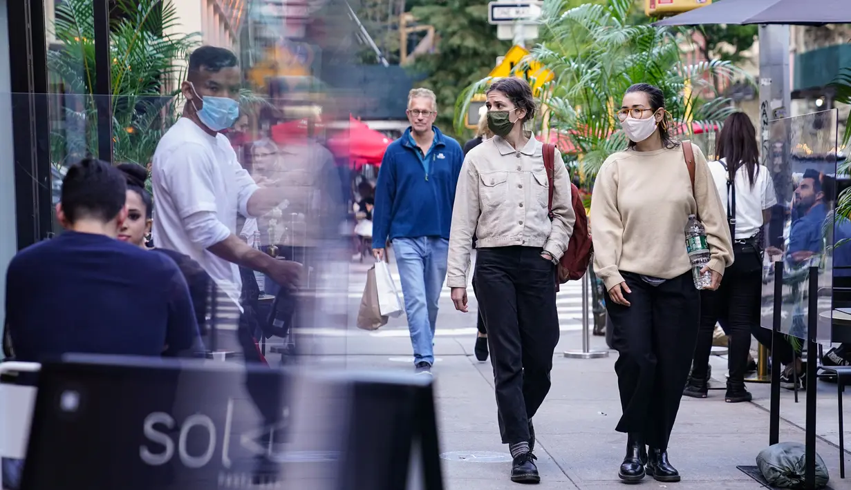 Orang-orang melewati pengunjung di luar restoran yang menawarkan layanan area outdoor di New York pada 3 Oktober 2020. Kota itu mengizinkan restoran membuat area makan outdoor hingga ke trotoar dan jalanan sebagai upaya mengatasi dampak ekonomi COVID-19 yang berkelanjutan. (AP Photo/John Minchillo)