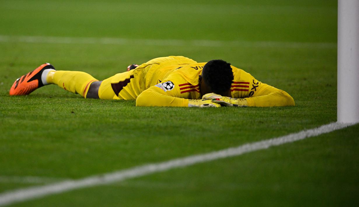 Kiper Manchester United, Andre Onana berbaring di lapangan setelah kebobolan gol pertama melalui tendangan gelandang Bayern Munchen, Leroy Sane pada laga matchday pertama Grup A Liga Champions 2023/2024 di Allianz Arena, Munich, Kamis (21/9/2023) dini hari WIB. (AFP/Tobias Schwarz)