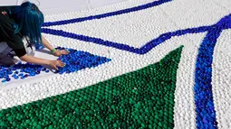 Relawan membuat mosaik raksasa dari 100 ton limbah tutup botol di kota Novi Sad, Serbia, Sabtu (30/9). Acara ini diselenggarakan badan amal nonpemerintah, Caps To Smiles dalam upaya peningkatan kesadaran bahaya pencemaran lingkungan. (AP/Darko Vojinovic)
