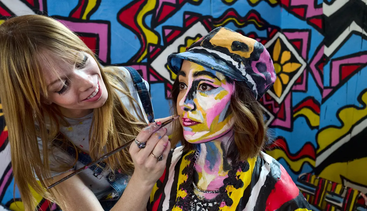 Seniman Alexa Meade (kiri) melukis wajah model Justine Jaime dalam instalasi seni 3D interaktif di Union Station, Los Angeles, Kamis (7/6). Acara ini digelar sebagai hiburan musim panas. (AP Photo/Richard Vogel)