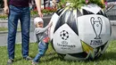 Seorang anak berdiri di sebelah pot bunga berbentuk seperti bola di Independence Square, Kiev, Ukraina (22/5). Final Liga Champions antara Real Madrid dan Liverpool akan berlangsung pada 26 Mei mendatang di Olimpiyskiy Stadion. (AFP Photo/Sergei Supinsky)