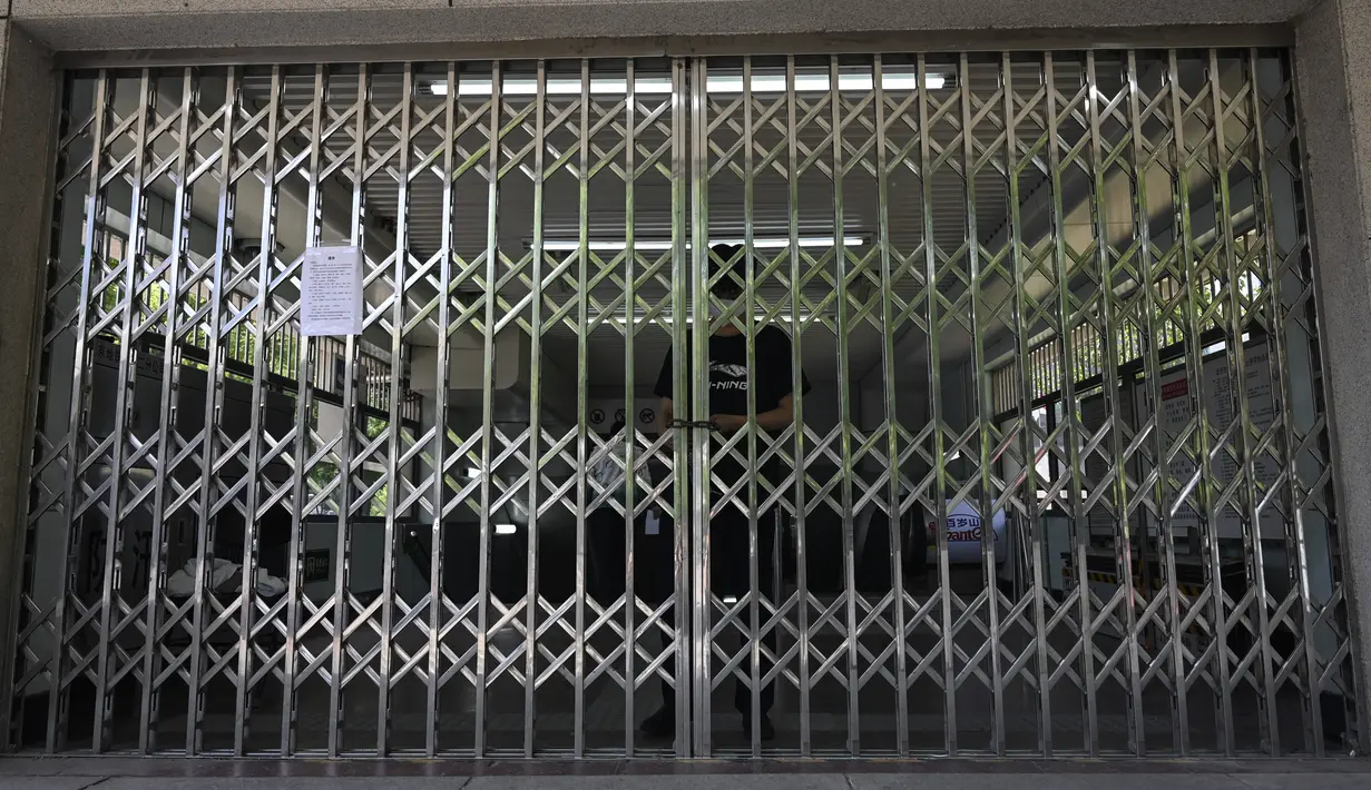 <p>Seorang pria mengunci gerbang stasiun kereta bawah tanah di kawasan pusat bisnis di Beijing, Rabu (4/5/2022). Beijing pada hari Rabu ini menutup lebih dari 40 stasiun kereta bawah tanah, sekitar sepersepuluh dari jaringan kereta, sebagai bagian dari tindakan untuk menghentikan penyebaran Covid-19. (Giok GAO / AFP)</p>