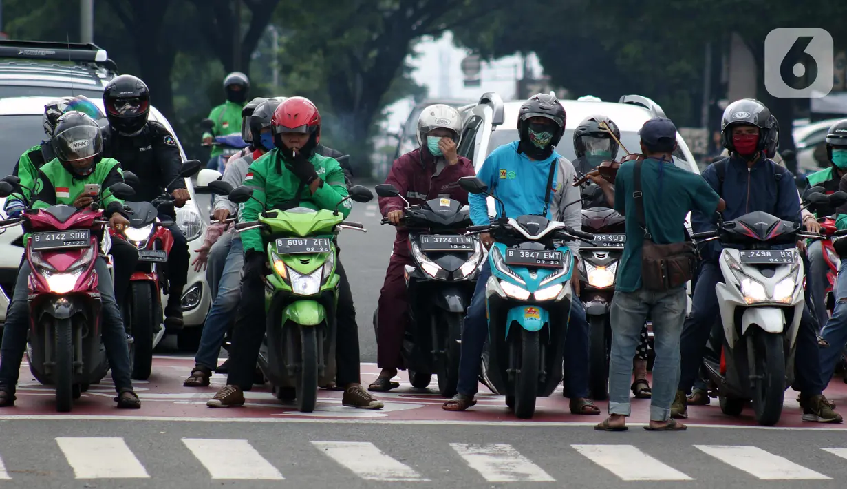 Pengendara motor di pemberhentian lampu Merah, Kota Depok, Jawa Barat, Minggu (12/4/2020). Menteri Kesehatan menyetujui menerapkan Pembatasan Sosial Berskala Besar (PSBB) di wilayah Kota Depok yang akan dimulai, Rabu (15/4) dalam pencegahan meluasnya COVID-19. (Liputan6.com/Helmi Fithriansyah)