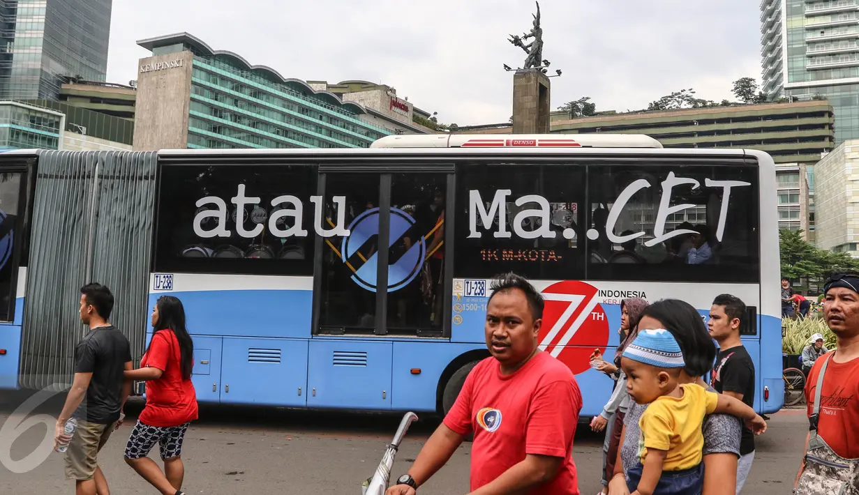 Sebuah bus TransJakarta koridor 1 dengan stiker bertuliskan Merdeka atau Macet melintas ketika masyarakat Jakarta tengah berolahraga saat Car Free Day (CFD) di kawasan Bundaran HI, Jakarta, (14/08). (Liputan6.com/Fery Pradolo).