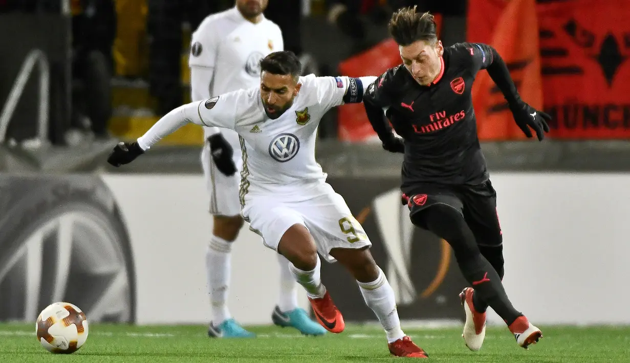 Pemain Ostersunds, Saman Ghoddos merebut bola dari  pemain Arsenal, Mesut Ozil pada laga leg pertama babak 32 besar Liga Europa di Jamtkraft Arena, Jumat (16/2). Arsenal memetik kemenangan 3-0 atas Ostersunds. (Robert Henriksson/TT News Agency via AP)