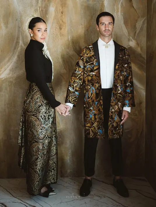 Sedangkan sang suami memilih atasan kemeja putih polos dengan bros kecil yang diletakkan di bagian kancing teratas, ditumpuk dengan outerwear dari batik yang serasi dengan yang dikenakan Adinia. Penampilannya semakin sempurna dengan paduan celana panjang berwarna hitam. Foto: Instagram.