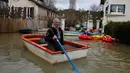 Seorang pria menggunakan perahu di jalan banjir di pulau Vaux, sebelah barat Paris, (30/1). Meluapnya sungai Seine di Paris membuat kebun dan jalan terendam banjir. (AP Photo / Thibault Camus)