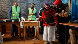 Lydia Gathoni Kiingati (102) menggunakan tongkat mendatangi sebuah TPS untuk memberikan suaranya di Gatundu, utara Nairobi, Selasa (8/8). Masyarakat Kenya melaksanakan pesta demokrasi dengan memberikan suara pada pemilihan presiden. (AP Photo/Ben Curtis)