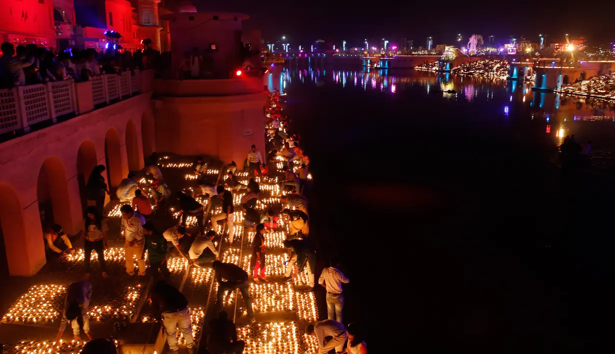 Masyarakat India menyalakan lampu dari tanah liat pada festival Diwali di tepi Sungai Sarayu, Ayodhya, Selasa (6/11). Kota di utara India itu memecahkan rekor dunia Guinness setelah menyalakan 300.150 lampu selama 45 menit. (AP/Rajesh Kumar Singh)
