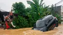Pihak berwenang telah mengerahkan helikopter dan perahu untuk mengevakuasi warga yang terjebak dan pasien kritis dari lokasi banjir. Tampak dalam foto, dua pemuda melihat sebuah mobil yang terendam banjir tinggi di Hat Yai, Provinsi Songkhla, Thailand selatan, pada Rabu 26 November 2025. (Arnun Chonmahatrakool/THAI NEWS PIX/AFP)