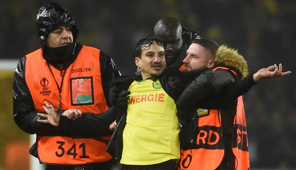 Pihak keamanan menangkap seorang suporter yang masuk ke lapangan dalam laga leg kedua play-off babak Liga Europa 2022/2023 antara Nantes melawan Juventus yang berlangsung di Stade de la Beaujoire, Jumat (24/2/2023). (AFP/Sebastien Salom-Gomis)