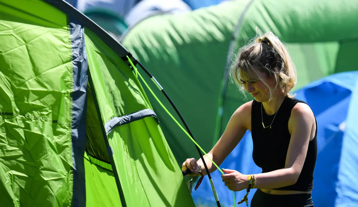 Seorang wanita mempersiapkan tenda di lokasi perkemahan pada hari pertama festival Glastonbury di desa Pilton, di Somerset, Inggris Barat Daya (22/6/2022). Lebih dari 200.000 penggemar musik dan megabintang Paul McCartney, Billie Eilish, dan Kendrick Lamar turun ke pedesaan Inggris minggu ini saat Festival Glastonbury kembali setelah jeda tiga tahun. (AFP/Andy Buchanan)