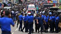 Polisi mensterilkan jalan saat sebuah ambulans melaju membawa korban ledakan gereja di Kochchikade, Kolombo, Sri Lanka, Minggu (21/4). Sekitar 99 orang dilaporkan tewas dalam ledakan di tiga gereja dan tiga hotel di Sri Lanka. (AP Photo/Eranga Jayawardena)
