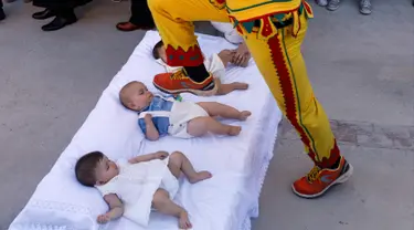 Pria berkostum setan melompati bayi-bayi yang terlentang di atas matras di sebuah jalan selama festival El Colacho di desa Castrillo de Murcia, Spanyol, Minggu (18/6). Festival melompati bayi ini sudah menjadi perayaan tahunan sejak 1620 (CESAR MANSO/AFP)