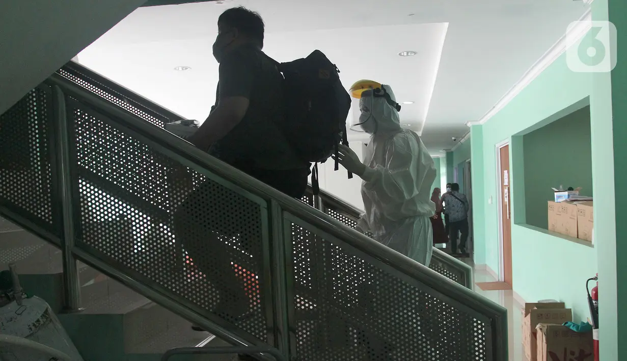 Paramedis berjalan dengan pasien positif COVID-19 di Puskesmas Jurumudi, Tangerang, Banten, Kamis (17/2/2022). Kasus positif COVID-19 di Kota Tangerang terus mengalami penurunan kasus dari 2000 kasus perhari menjadi 1000 kasus perhari. (merdeka.com/Arie Basuki)