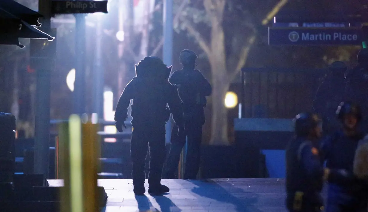 Polisi memakai pakaian lapis baja berjalan di dekat Kafe Lindt di Martin Place, Sydney (16/12/2014). Seorang pria bersenjata masuk ke Kafe Lindt dan menyandera beberapa orang yang berada di dalam kafe tersebut. (REUTERS/Jason Reed)
