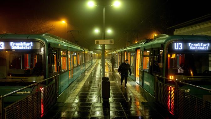 Seorang perempuan berjalan menjauh dari stasiun kereta bawah tanah saat hujan di Oberursel dekat Frankfurt, Jerman, pada 12 November 2020, ketika jumlah infeksi covid-19 melebihi 20.000 lagi. (AP Photo/Michael Probst)