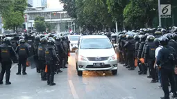 Kendaraan melintas di antara polisi yang berjaga di sekitaran Stasiun Palmerah, Jakarta, Senin (30/9/2019). Jalur di kawasan itu telah dibuka, namun kendaraan harus berhati-hati karena banyaknya batu sisa bentrokan massa di belakang gedung DPR yang berakhir ricuh. (Liputan6.com/Angga Yuniar)