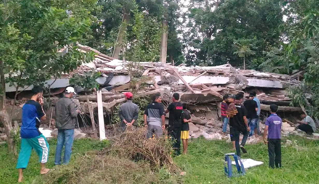 Warga berkumpul di sekitar bangunan roboh menyusul gempa 6,4 SR yang mengguncang Kabupaten Pidie Jaya, Aceh, Rabu (7/12). Empat orang dikabarkan meninggal dunia dan sekitar 30 warga mengalami luka-luka akibat tertimpa bangunan roboh. (Zian Muttaqien/AFP)