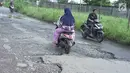 Pengendara sepeda motor melintasi jalan yang rusak di Jalan Raya Gas Alam, Depok, Jawa Barat, Selasa (7/5). Kondisi jalan yang tidak kunjung diperbaiki tersebut menjadi kubangan air setiap hujan serta berbahaya bagi keselamatan pengguna jalan. (Liputan6.com/Immanuel Antonius)