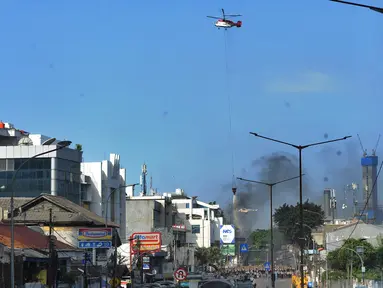 Helikopter water bombing menyiramkan air ke arah ban yang dibakar massa di kawasan Slipi, Jakarta, Rabu (22/5/2019). Air dijatuhkan dari udara ke arah api yang berasal dari ban bekas. (merdeka.com/Arie Basuki)