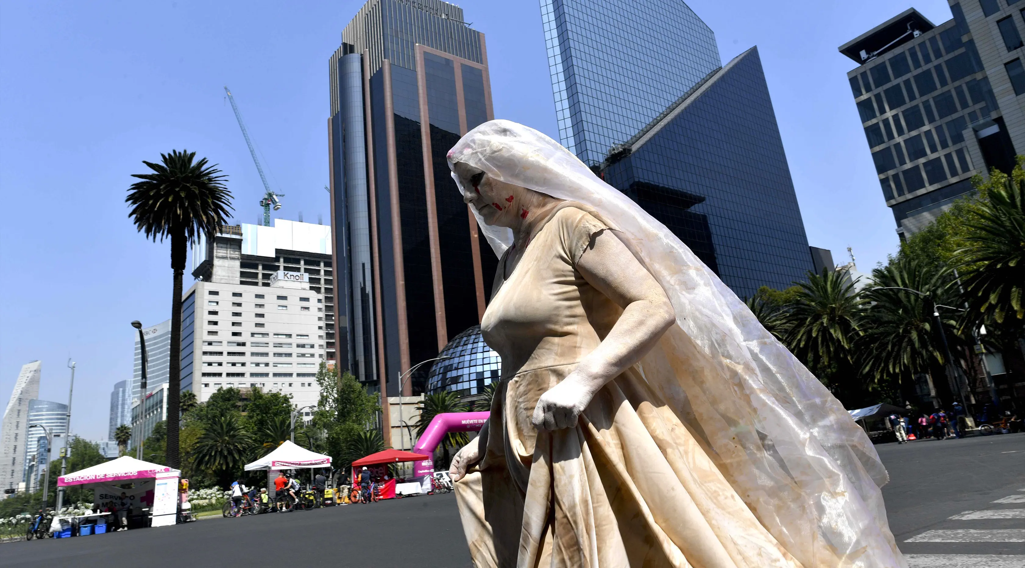 Seorang wanita mengenakan gaun dan kerudung putih  dengan noda darah melintas di jalan Mexico City, Meksiko (7/5). Aksi 