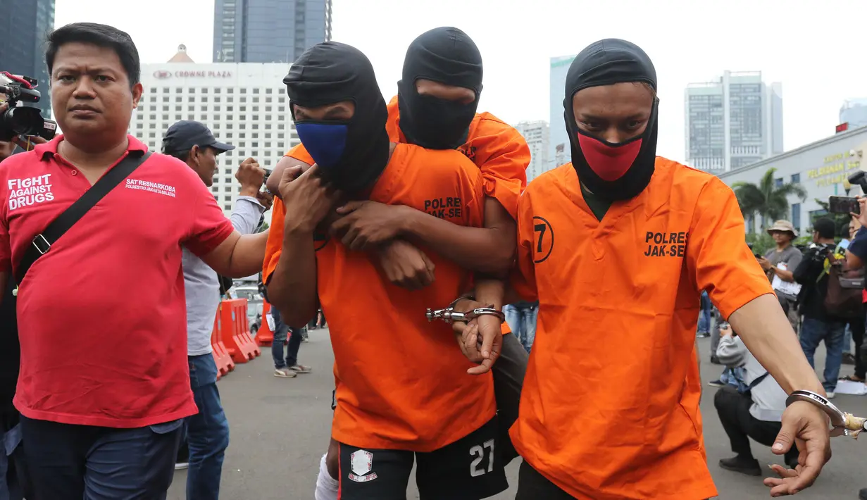 Petugas membawa sejumlah tersangka tindak kejahatan dalam rilis akhir tahun di Balai Polda Metro Jaya, Jumat (27/12/2019). Polisi juga menampilkan barang bukti ganja dengan total mencapai 1 ton yang diamankan dari setiap polres dan wilayah hukum Polda Metro Jaya. (Liputan6.com/Herman Zakharia)