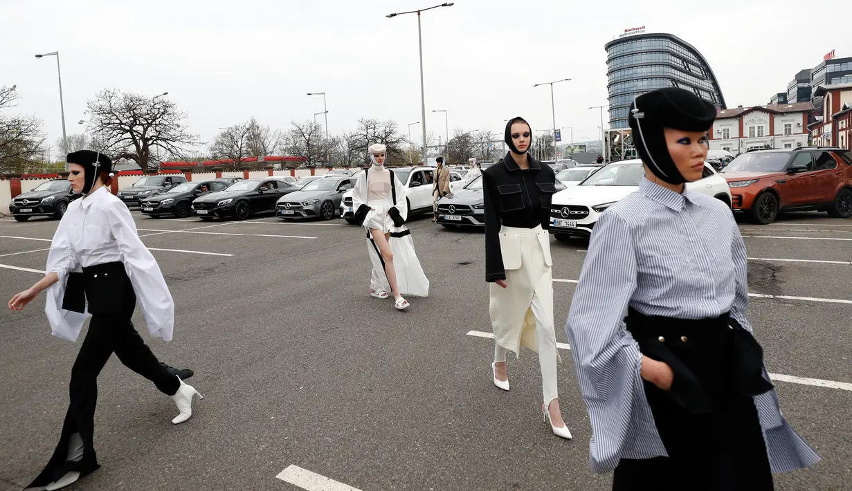 Para model berjalan melewati mobil saat drive-in fashion show bagian dari Praha Fashion Week di Praha, Republik Ceko, Sabtu (1/5/2021). Karena pembatasan virus corona, penonton hanya dapat melihat pertunjukan dari dalam mobil mereka. (AP Photo/Petr David Josek)
