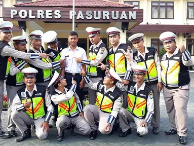 Pria bernama Polisi (Kemeja putih) berpose dengan anggota kepolisian di halaman Polres Pasuruan (21/11). Remaja 22 tahun asal Dusun Pengarengan, Pasuruan, mulai bekerja di Mapolres Pasuruan, Senin (20/11/2017) pagi. (AFP Photo)