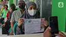Petugas memotret warga penerima Bantuan Sosial Tunai (BST) di kawasan Kelurahan Kembangan, Meruya, Jakarta Barat, Minggu (25/07/2021). Kementerian Sosial melalui PT Pos Indonesia mulai menyalurkan BST yang dirapel dua bulan sekaligus dengan total Rp600ribu. (Liputan6.com/Herman Zakharia)
