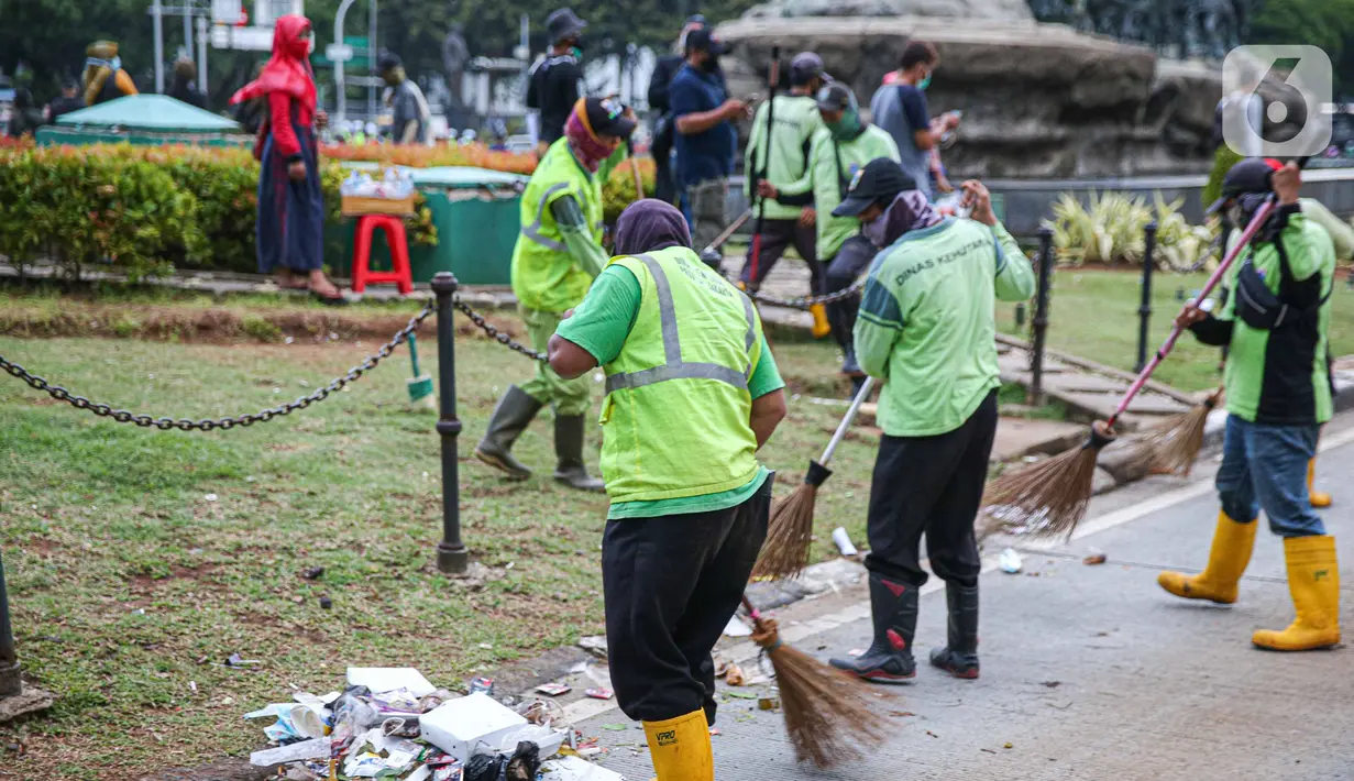 Petugas kebersihan membersihkan sampah sisa pendemo usai unjuk rasa buruh di kawasan Patung Kuda, Jakarta, Kamis (22/10/2020). Sebelumnya, buruh dari berbagai elemen berunjuk rasa menolak pengesahan Omnibus Law UU Cipta Kerja. (Liputan6.com/Faizal Fanani)