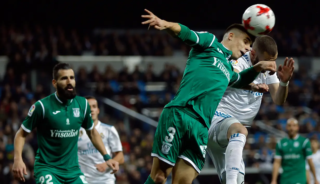 Pemain Real Madrid, Karim Benzema dan pemain Leganes, Unai Bustinza berebut menyundul bola pada leg kedua perempatfinal Copa del Rey di Santiago Bernabeu, Kamis (25/1). Bermain di kandang sendiri, Real Madrid menyerah 1-2. (AP/Francisco Seco)