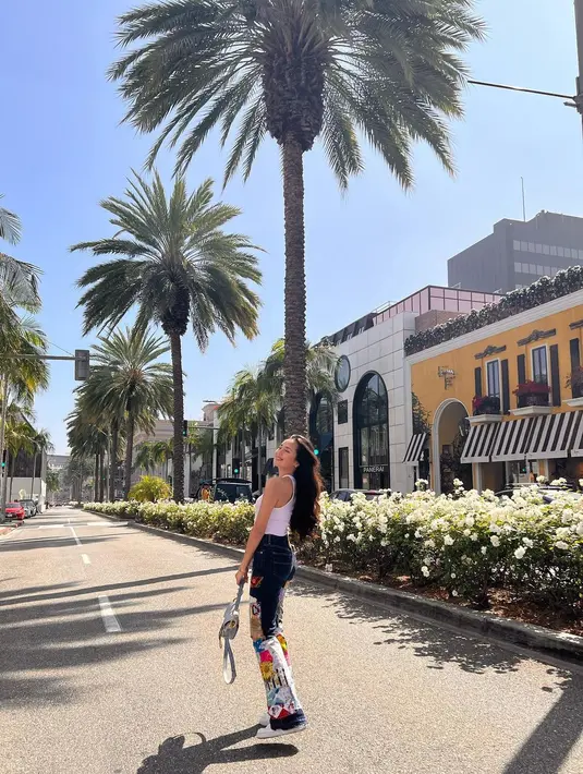 Berpose di spot-spot terbaik, Beby Tsabina tampil kasual dengan crop top putih. Rambut panjangnya dibiarkan terurai, Beby Tsabina tampak memadukan crop top putihnya dengan celana jeans bercorak yang colorful, sneakers putih, dan tas Dior. Foto: Instagram.