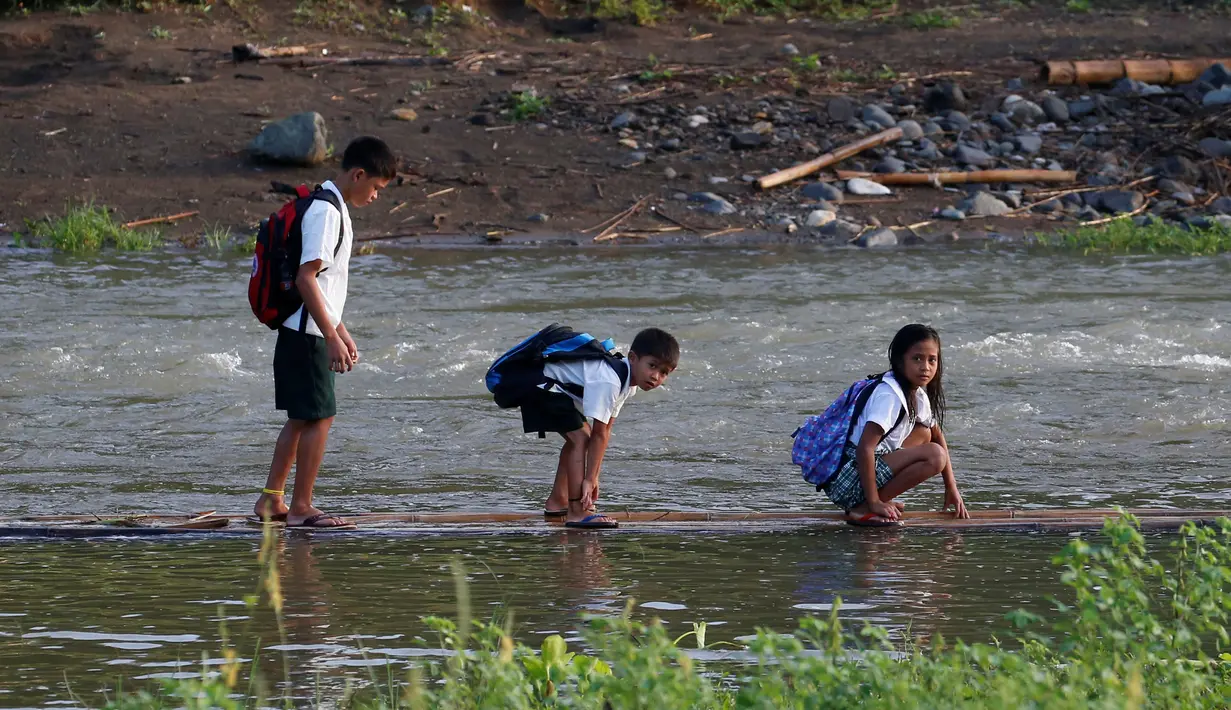 Sejumlah bocah saat menyeberangi sungai untuk menuju sekolah di sebuah desa terpencil di Montalban, Rizal, Filipina, Senin (13/6). Tidak adanya fasilitas jembatan membuat para siswa mempertaruhkan keselamatannya. (REUTERS/Erik De Castro)