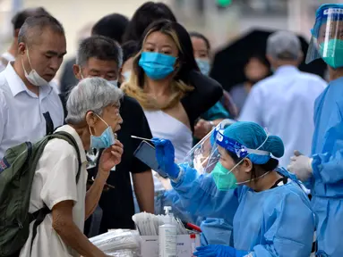 Seorang pekerja yang mengenakan pakaian pelindung menyeka tenggorokan seorang wanita untuk tes COVID-19 di fasilitas pengujian virus corona di Beijing, China, Jumat (12/8/2022). Beberapa kota di China yang dilanda COVID-19 dari timur ke barat negara itu memberlakukan pembatasan dan lockdown baru untuk menahan gejolak yang sekali lagi mengancam akan mengganggu ekonomi lokal. (AP Photo/Mark Schiefelbein)
