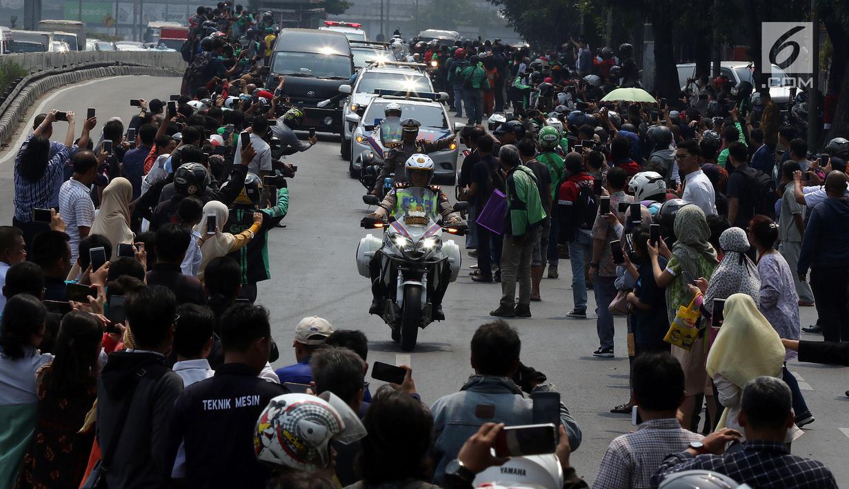 Warga mengambil gambar iring-iringan mobil jenazah yang membawa almarhum Presiden ke-3 RI, BJ Habibie saat melintasi Jalan Gatot Subroto menuju TMP Kalibata, Jakarta, Kamis (12/9/2019). BJ Habibie meninggal pada Rabu (11/9/2019) setelah menjalani perawatan di RSPAD. (Liputan6.com/Johan Tallo)